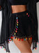 Black shorts with colorful tassels on a plain background