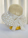 Chapeau de soleil beige orné de dentelle florale blanche sur fond blanc