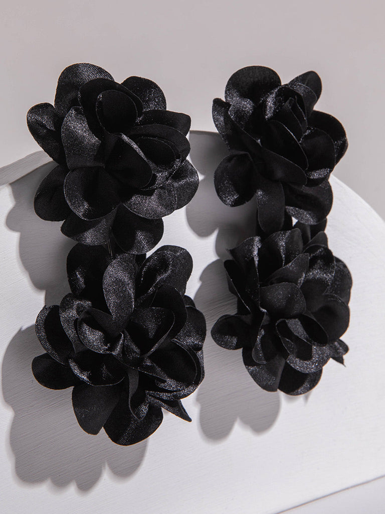Boucles d'oreilles pendantes noires audacieuses ornées de groupes de quatre fleurs en tissu, offrant un effet floral 3D et texturé spectaculaire.