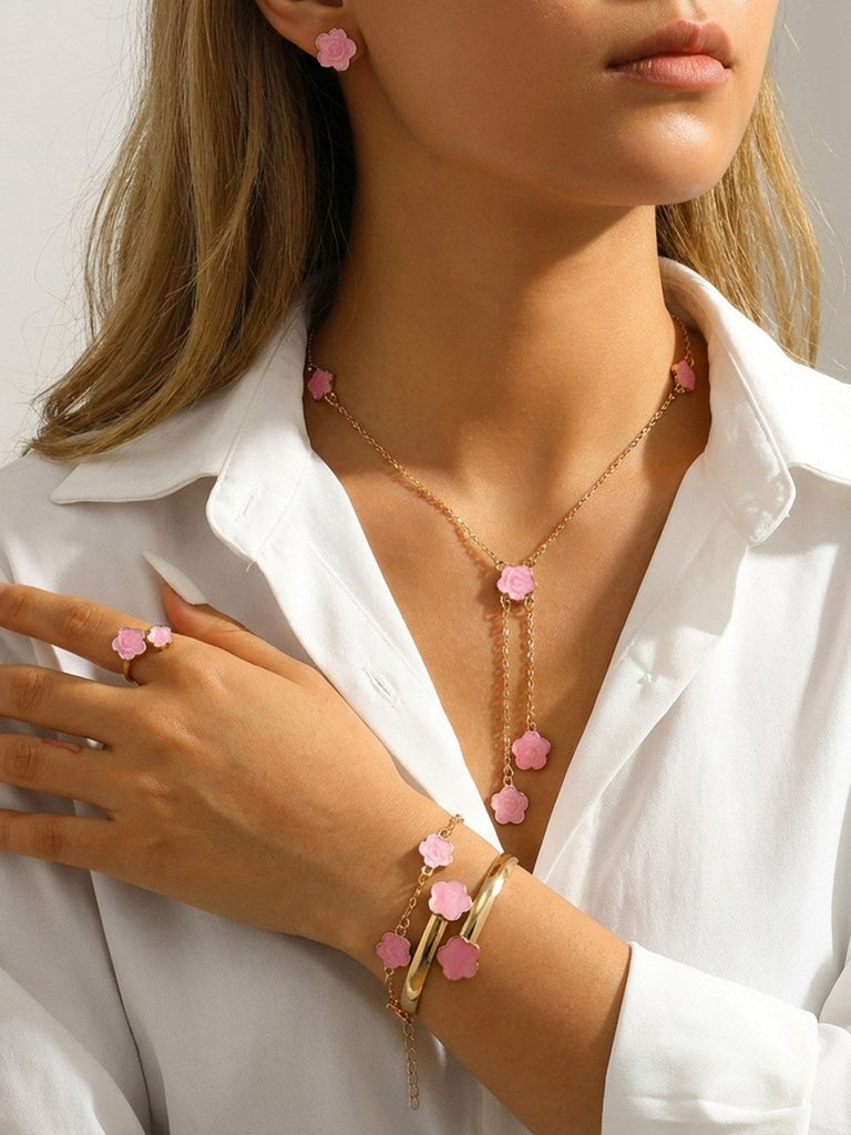 Person wearing a Pink necklace with pink floral pendants, matching ring, and bracelet on a white background.