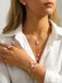 Person wearing a Pink necklace with pink floral pendants, matching ring, and bracelet on a white background.