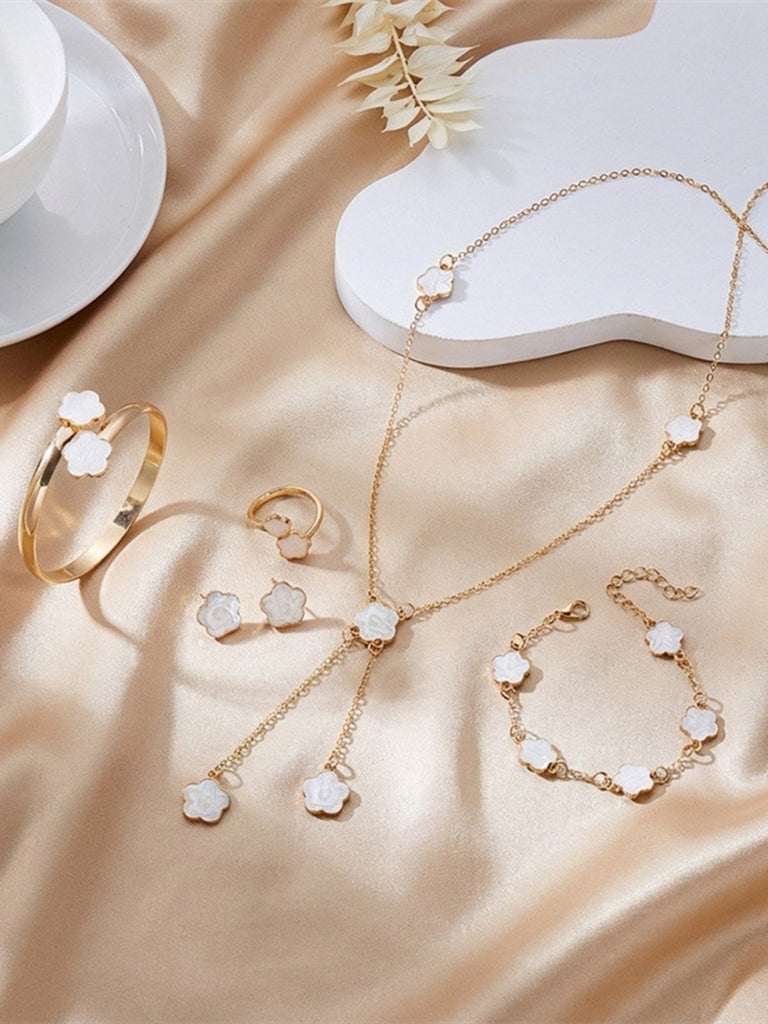 White jewelry set with rings, bracelet, and necklace on a beige fabric background