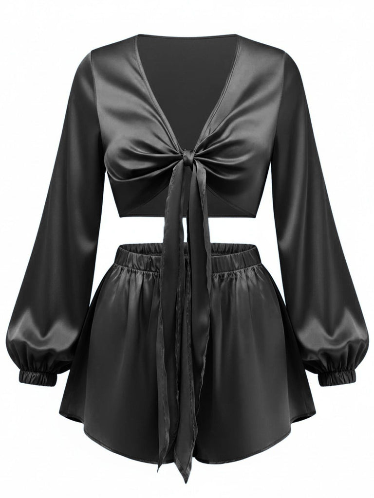 Cet ensemble deux pièces en satin soyeux à nouer sur le devant est présenté ici en noir classique pour un look lounge sophistiqué.