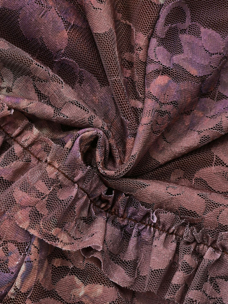 Macro view of the exquisite purple floral embroidery and mesh lace fabric with soft pleated details.