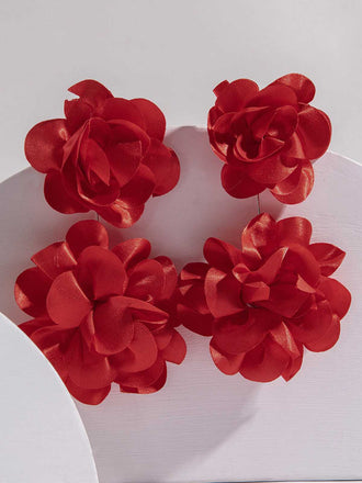 A pair of red statement earrings with multiple tiered fabric flower petals arranged in a cluster on a plain background.