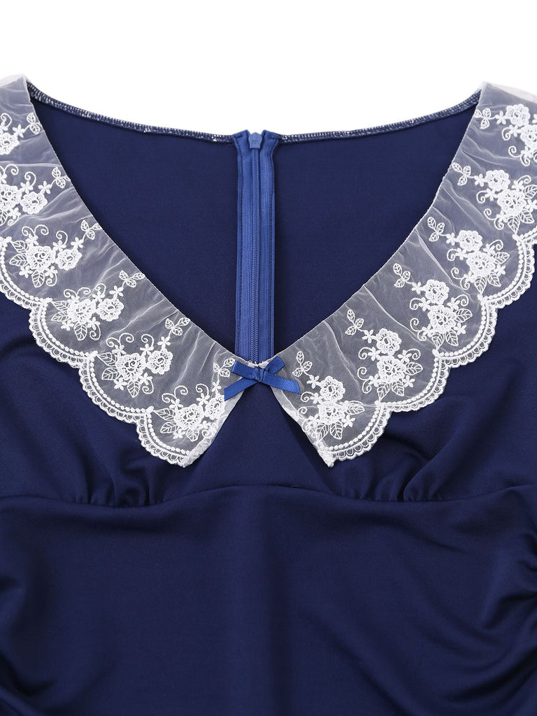 Close-up of the delicate white floral lace collar and the center blue ribbon bow on the navy dress.